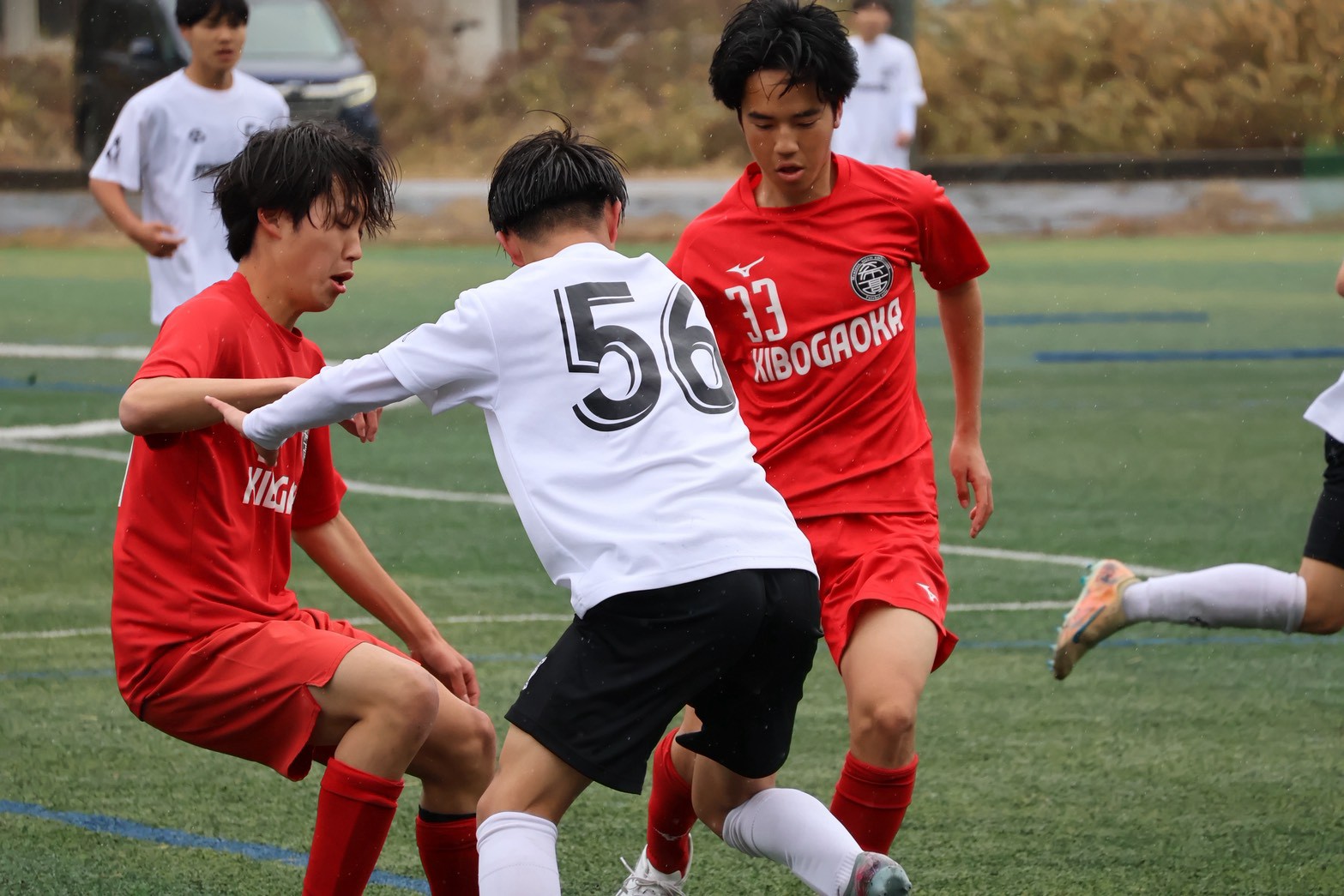 雨のピッチでボールを競り合う希望ケ丘の選手たち